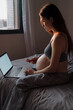 © Artem Zhushman/Stocksy - Pregnant woman shops online in bed