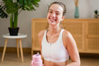 © mahalo studio/Stocksy - woman posing holding water bottle after home workout