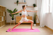 © mahalo studio/Stocksy - woman practicing yoga warrior two pose at home