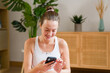 © mahalo studio/Stocksy - woman using smartphone app after home workout session