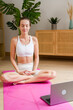 © mahalo studio/Stocksy - woman practicing online meditation at home with laptop