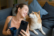 © mahalo studio/Stocksy - Woman taking selfie with shiba inu dog on sofa