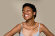 © mahalo studio/Stocksy - woman smiling with eyes closed on beige background