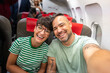 © Alvaro Lavin/Stocksy - Happy couple taking selfie on airplane during flight