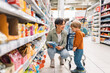 © Santi Nuñez/Stocksy - Mother shopping with her young son in a grocery store aisle