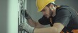 © Morto - A detailed shot of an electrician installing wiring in a newly constructed office space, Electrical installation scene, Technical and meticulous style