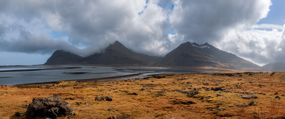 Wall Mural - mountains at icelandic sea shore with dramatic cloudy sky.