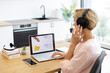 © Sofiia Shunkina - Happy Caucasian woman ordering food online on delivery website using laptop while listening to music in headphones. She is sitting at home with light background.