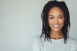 © olegganko - Portrait of a woman with long dreadlocks smiling against a light background