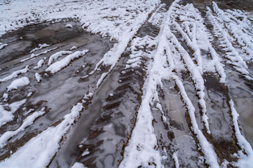 Tire tracks in the ice mud of winter in rural with snow. Off-road in frozen land. Landscape nature background.