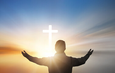Wall Mural - silhouette of a man praying with a cross in the background