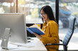 © NINENII - Asian businesswoman sits in a office reading a book at leisure and enjoys a coffee.