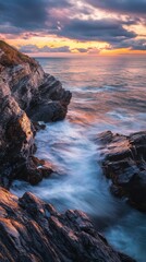 Aufkleber - The sun sets over the Atlantic Ocean, casting a warm glow on the rocky shoreline. Gentle waves create a soothing rhythm as they wash against the cliffs, highlighting nature's beauty.
