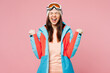 © ViDi Studio - Skier young woman in warm blue padded jacket ski goggles mask spend extreme weekend winter season in mountains do winner gesture celebrate clench fist isolated on plain pink background Hobby concept