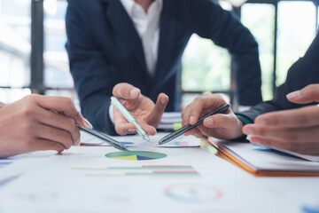 Wall Mural - Strategic Collaboration: Hands actively engaged with financial charts, showcasing a focused business meeting and collaborative problem-solving.  A candid depiction of teamwork and strategic planning.