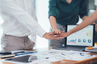© Nittaya - Teamwork Makes the Dream Work: A close-up shot of diverse business colleagues stacking their hands together, symbolizing unity, collaboration, and shared goals.