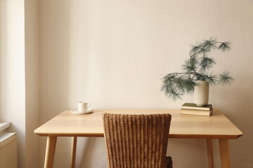 Wall Mural - Christmas breakfast still life. Minimal winter composition. White cup of coffee, tea, plate. Pine tree branches in vase, old books on wooden table with rattan chair. Elegant Scandinavian living room.