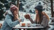 © Ceyhun - Women standing in a wintery park, one pours hot drink from a thermos