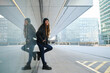 © Cavan Images - Young stylish woman leaning against glass wall in modern city setting