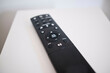 © Connect Images - Black remote control resting on a white surface with buttons in focus.