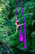 © Connect Images - An aerial silk performer executes a pose with purple fabric against a lush forest backdrop, USA