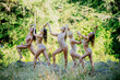 © Connect Images - Five women perform a synchronized dance routine in a forest clearing, wearing coordinated attire and striking elegant poses, USA