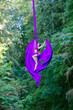 © Connect Images - Aerial silk performer executes a pose with purple fabric in a lush green forest setting, USA