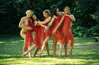 © Connect Images - Five female dancers in red drapes perform a dance routine in a sunlit forest clearing, USA.