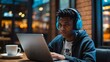 © LIFE LINE - Black teenager gaming on a laptop in a café wearing headphones with blank space