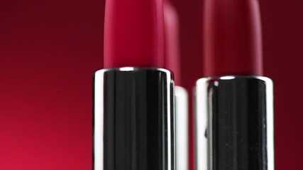 Wall Mural - Lipstick. Fashion red Colorful Lipsticks on red background, close up. Red lipstick tints palette, Professional Makeup and beauty. Beautiful Make-up concept. Lipgloss. Lipsticks closeup. 