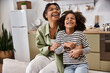 © LIGHTFIELD STUDIOS - A mother and her daughter are laughing together in a bright kitchen, sharing a loving moment.