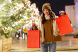 © Home-stock - Excited lady with shopping bags on traditional city street Christmas market. Merry Xmas and Happy New Year festive shopping