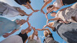 © Довидович Михаил - Group of young women is standing in a circle, joining their hands together against a blue sky.