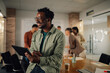 © Zamrznuti tonovi - Smiling businessman using digital tablet in modern office with colleagues working