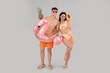 © Pixel-Shot - Happy young couple with exotic fruits, inflatable ring in shape of flamingo on grey background