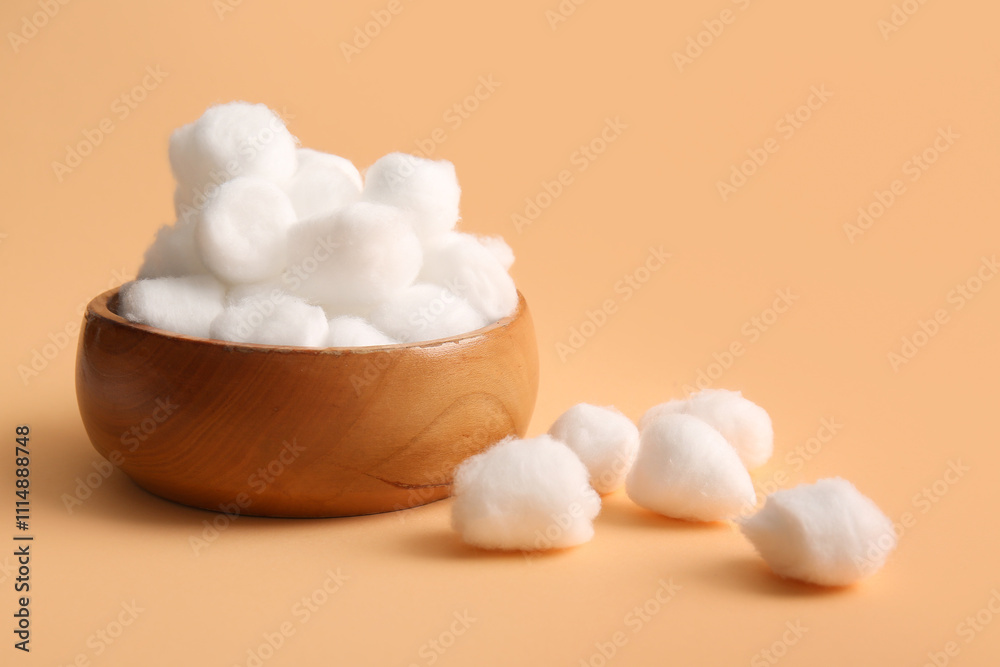 Wooden bowl with cotton balls on brown background