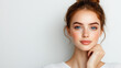 © NaphakStudio - young woman with blue eyes and natural makeup look, smiling gently while resting her chin on her hand against light background.