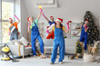 © Pixel-Shot - Team of janitors with Santa hats singing in room after New Year party