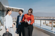© qunica.com - Three business colleagues in formal attire engage in a discussion on an outdoor terrace. The scene conveys professionalism, collaboration, and a sunny work environment, highlighting a productive