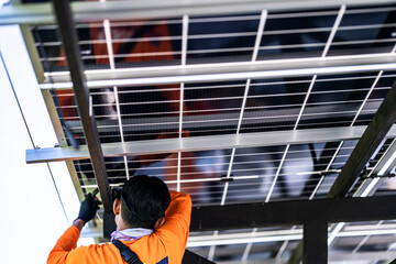 Wall Mural - worker in an orange safety uniform installing and wiring solar panels on a framework, showcasing the