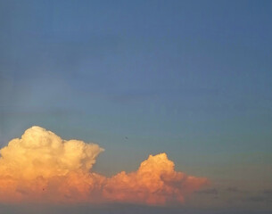 Golden cumulus clouds in a dark blue sky.  Sunset