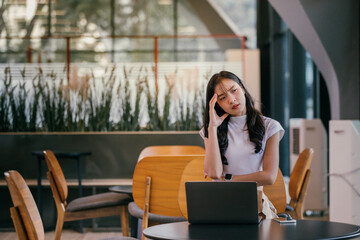 Aufkleber - young asian businesswoman is having a bad headache while working remotely on a laptop in a coworking