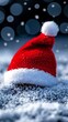 © VISUAL BACKGROUND - A red santa hat sitting on top of a snow covered ground