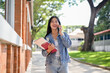 © bongkarn - A cheerful female student enjoys talking on the phone with her friend while on her way to class.