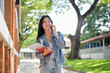 © bongkarn - A cheerful female student enjoys talking on the phone with her friend while on her way to class.