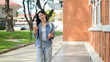 © bongkarn - An attractive Asian woman walks outdoors while reading texts on her smartphone on her way to class.