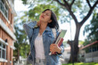 © bongkarn - A tired, sweaty Asian female college student feels hot and uncomfortable while walking outdoors.