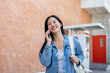© bongkarn - A cheerful female student enjoys talking on the phone with her friend while on her way to class.
