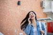 © bongkarn - A cheerful female student enjoys talking on the phone with her friend while on her way to class.