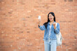 © bongkarn - A cheerful Asian female college student shows a victory fist, receiving good news through a message.
